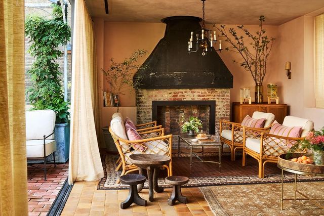 A sitting room at Hotel Chelsea, with rattan armchairs, a brick fireplace and doors onto a terrace